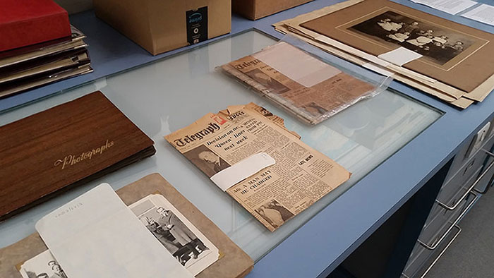 Newspapers, albums and loose photographs from the Hynd collection laid out for packaging