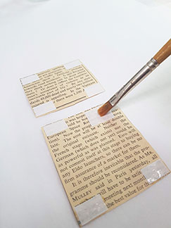 A close up of a conservator using a paintbrush to remove adhesive with a colourless acetone gel