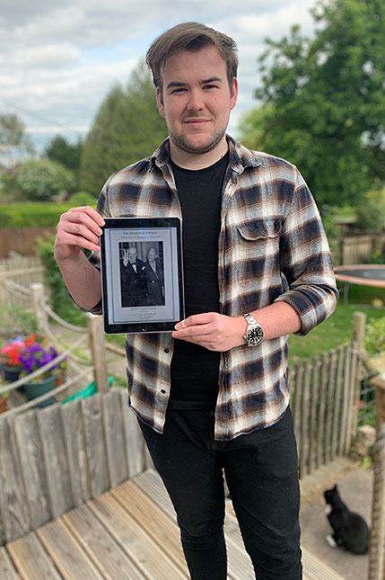 Elliot James Clark holding an iPad and showing the front page of his dissertation