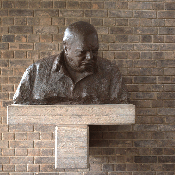 A photograph of Oscar Nemon's bust of Sir Winston Churchill on the stairs leading to the Dining Hall, Churchill College