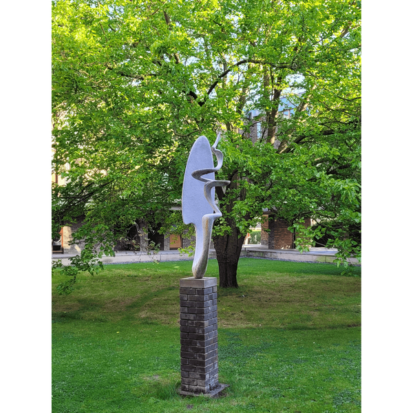 A photograph of Gillespie's sculpture, 'Spiral' against the backdrop of a tree in leaf.