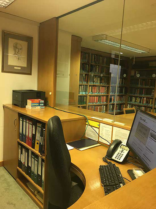 Photograph of the reading room issue desk at Churchill Archives Centre, including a portrait of Stephen Roskill on the wall behind
