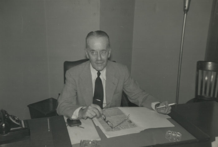 Black and white photo of Sir Alexander Cadogan seated at a desk