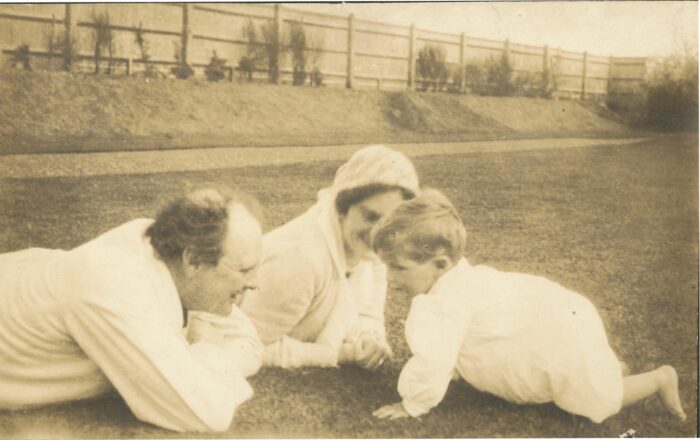 Sepia photo of Churchill and Clementine lying on the grass while their baby Randolph crawls towards them